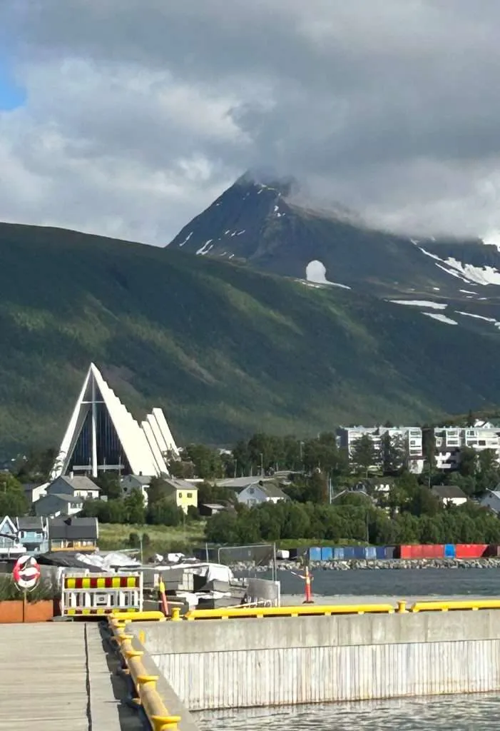 A white modern church with a snowy mountain in the background.