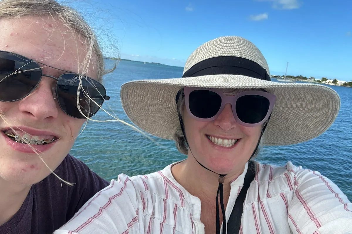 a woman and a teen boy smile with water in the background