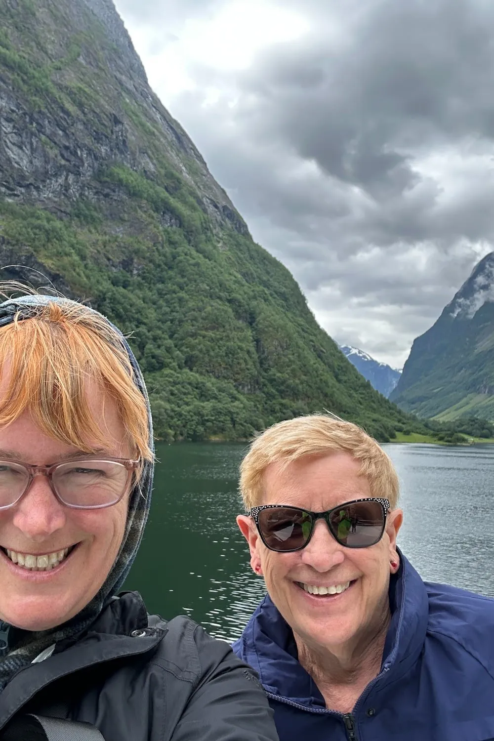 two women smile in front of a Norwegian fjord